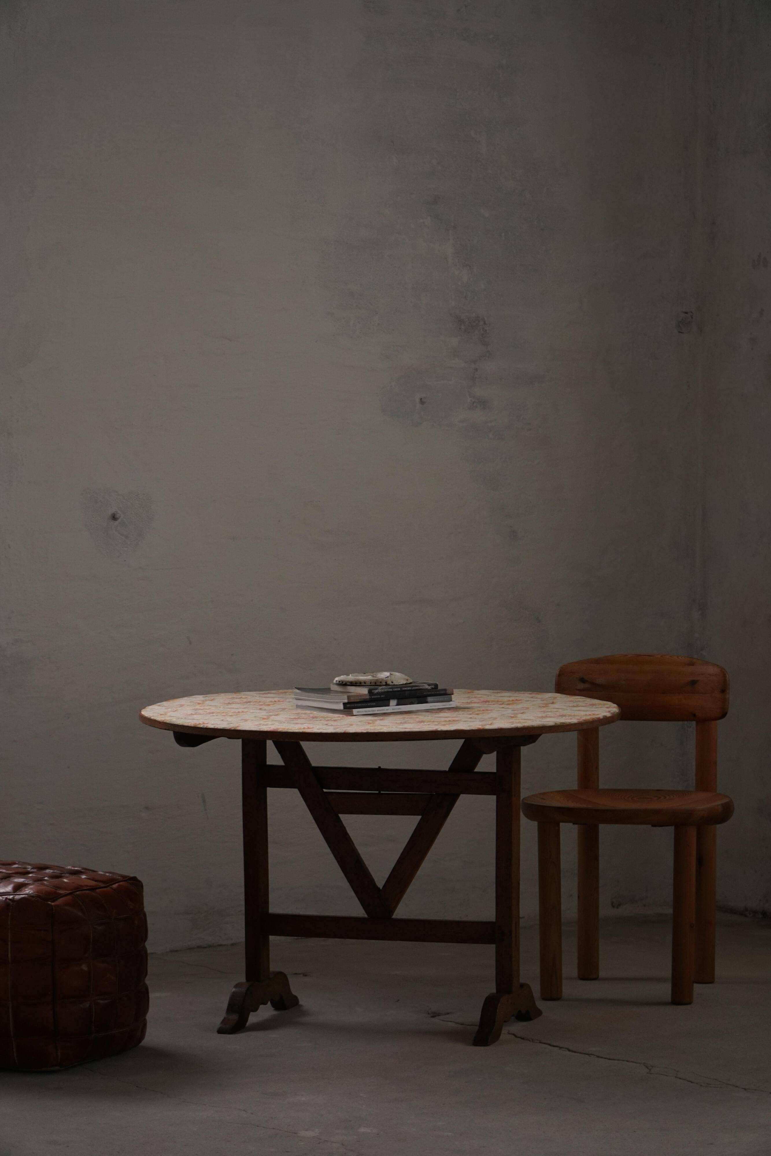 19th-century French round wine table with an adjustable top and floral textile surface.