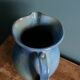 Enamel pitcher in pastel blue and green, signed