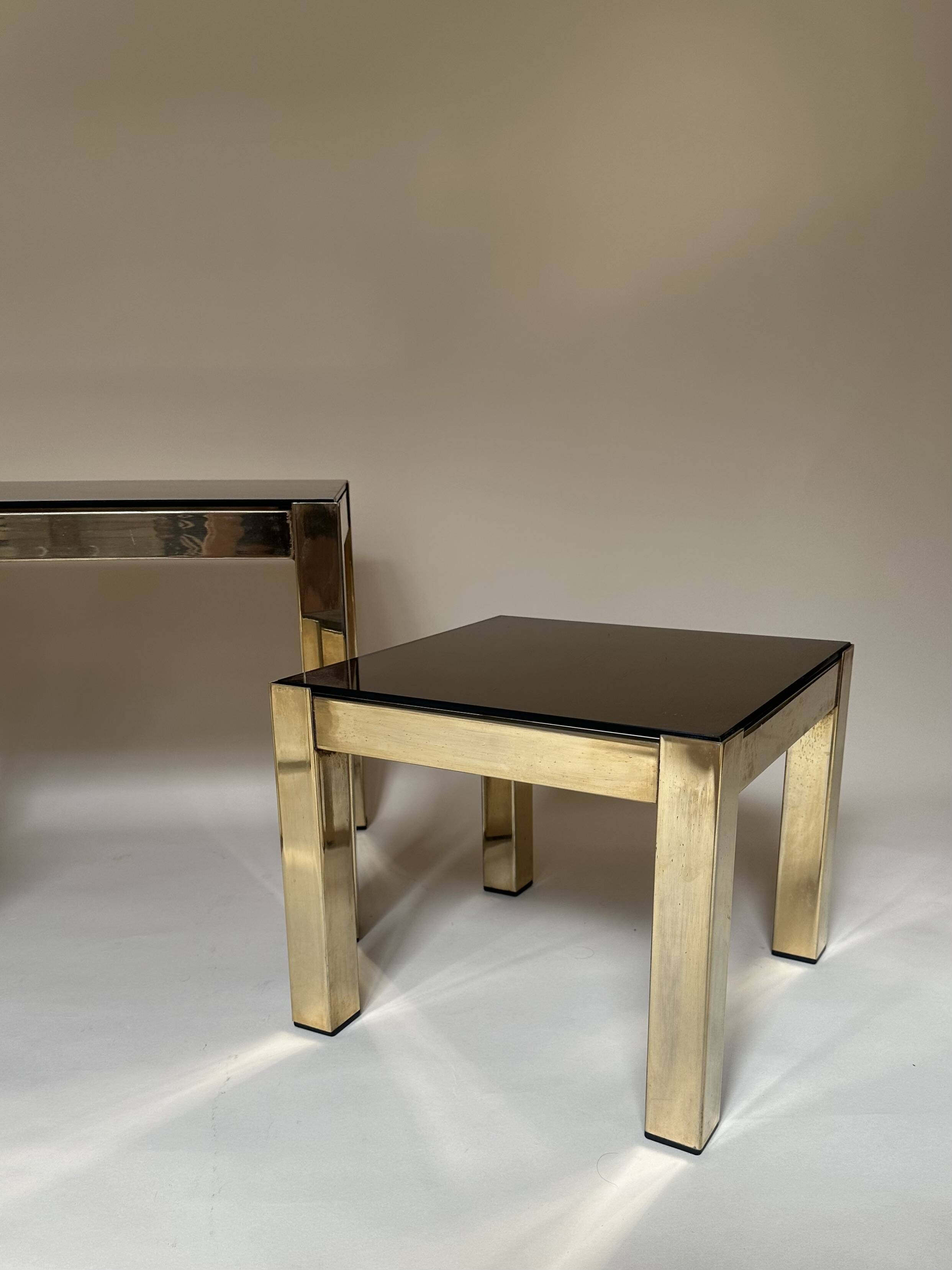 Set of three nesting side tables in brass and smoked mirror.