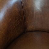 Subtle, neat sheepskin leather club armchair with a fixed seat cushion in a deep, dark cognac color