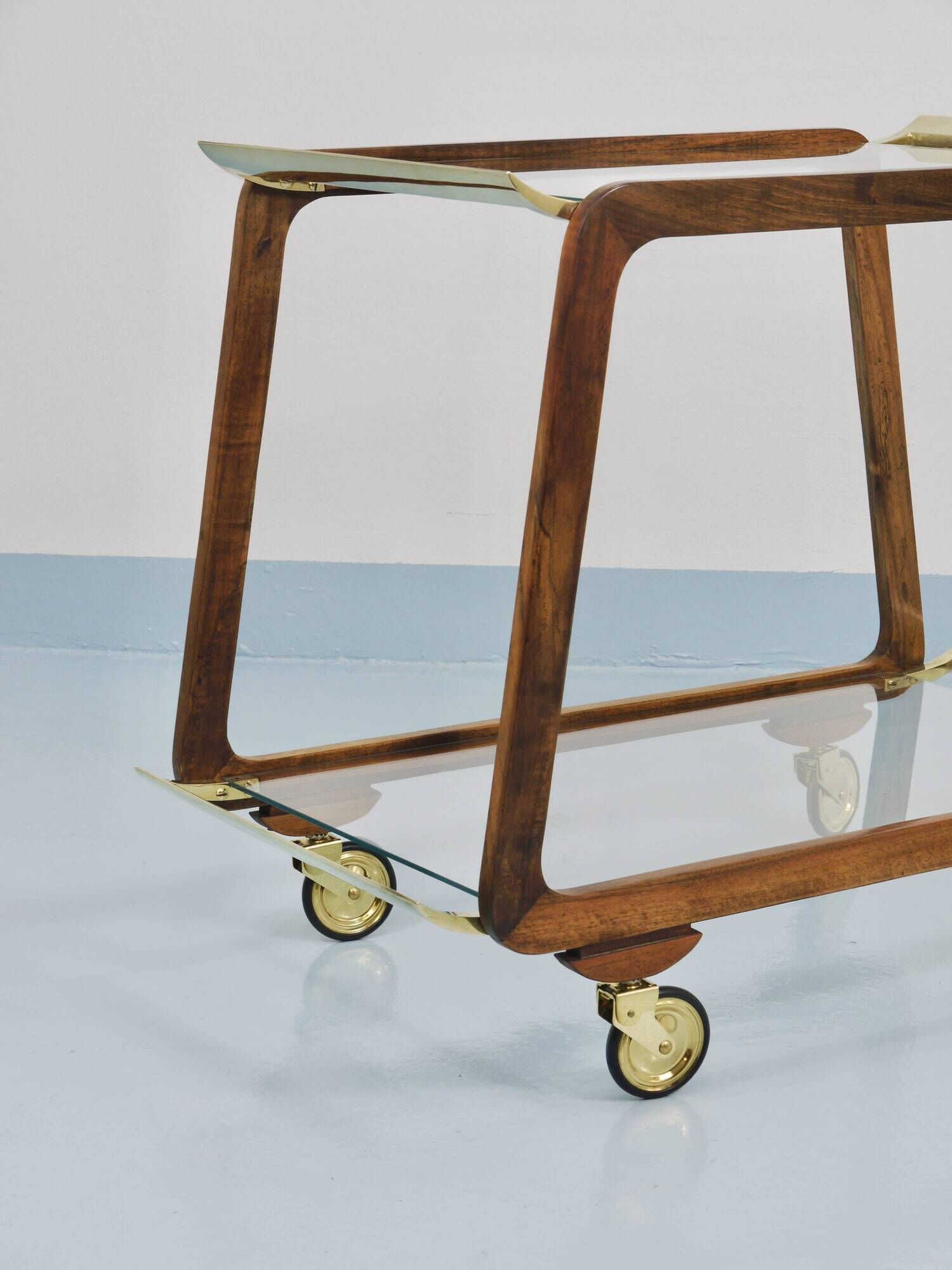 May include: A mid-century modern bar cart with a dark wood frame and two c