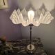 Table lamp with a silver base and a frilled shade.