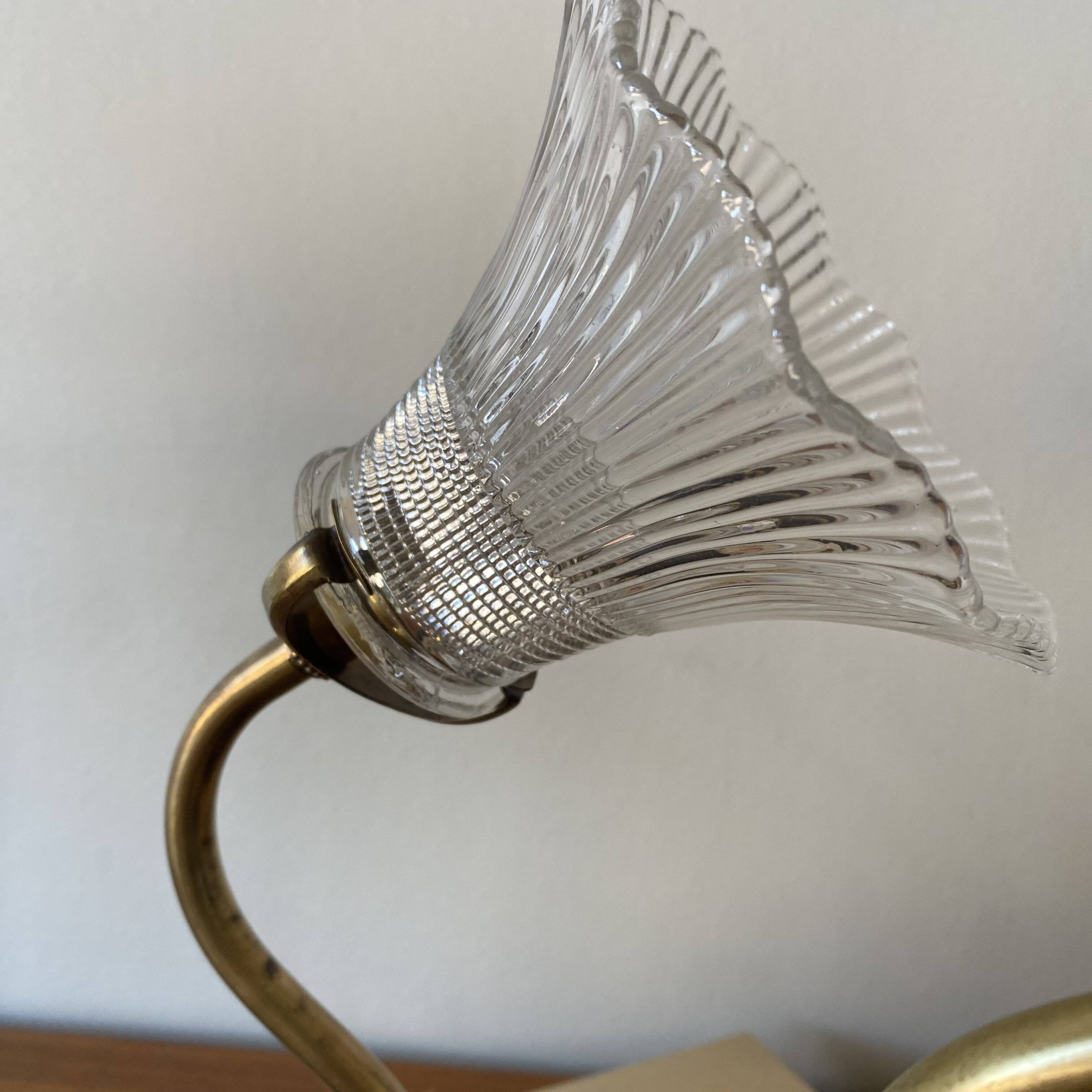 Pair of brass swan neck wall lights with transparent glass shades.