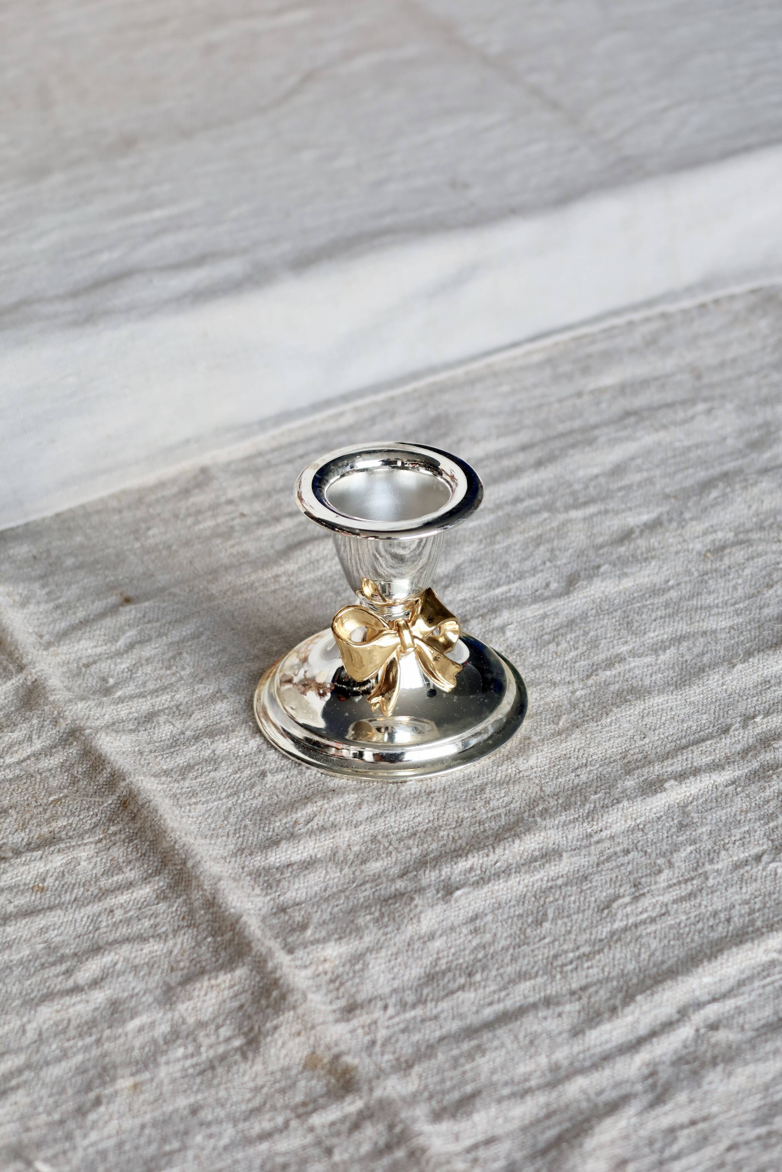 Small vintage silver-plated metal candlestick with a gold bow