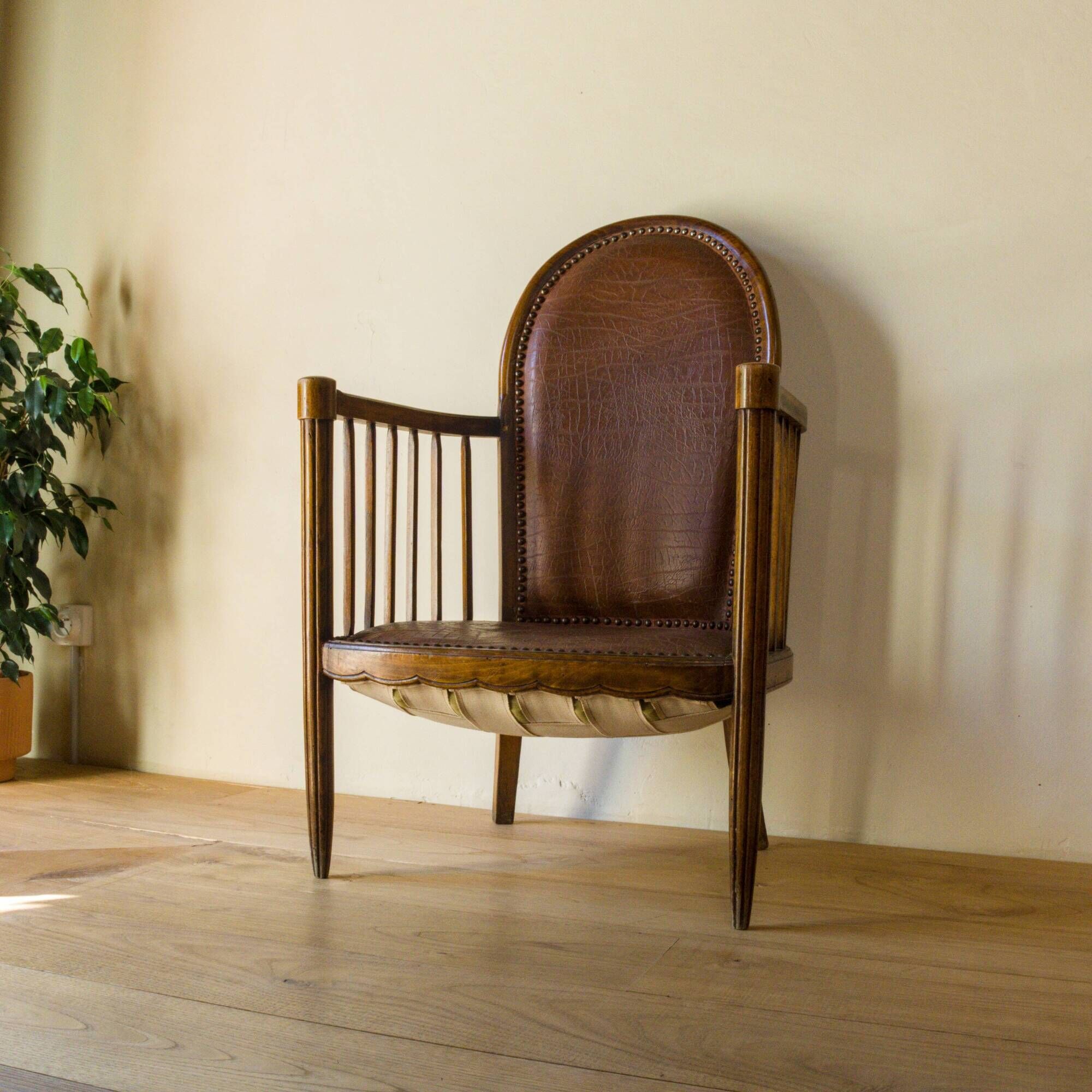 Antique armchair in solid wood and patinated brown leather, early 20th century.