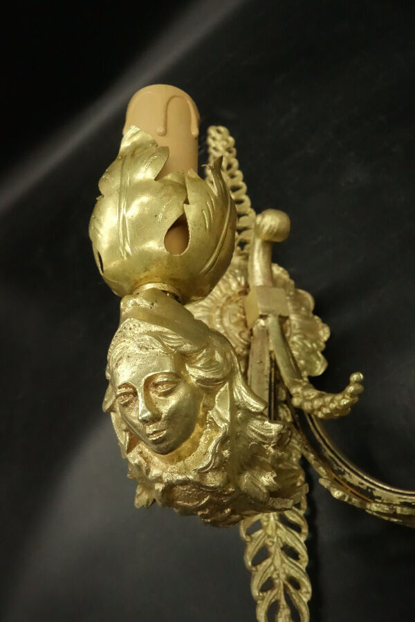 Pair of wall sconces with mask motifs in Empire style from the early 1900s - gilded bronze.