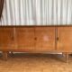 Vintage 4-door buffet with wood veneer and glass top.