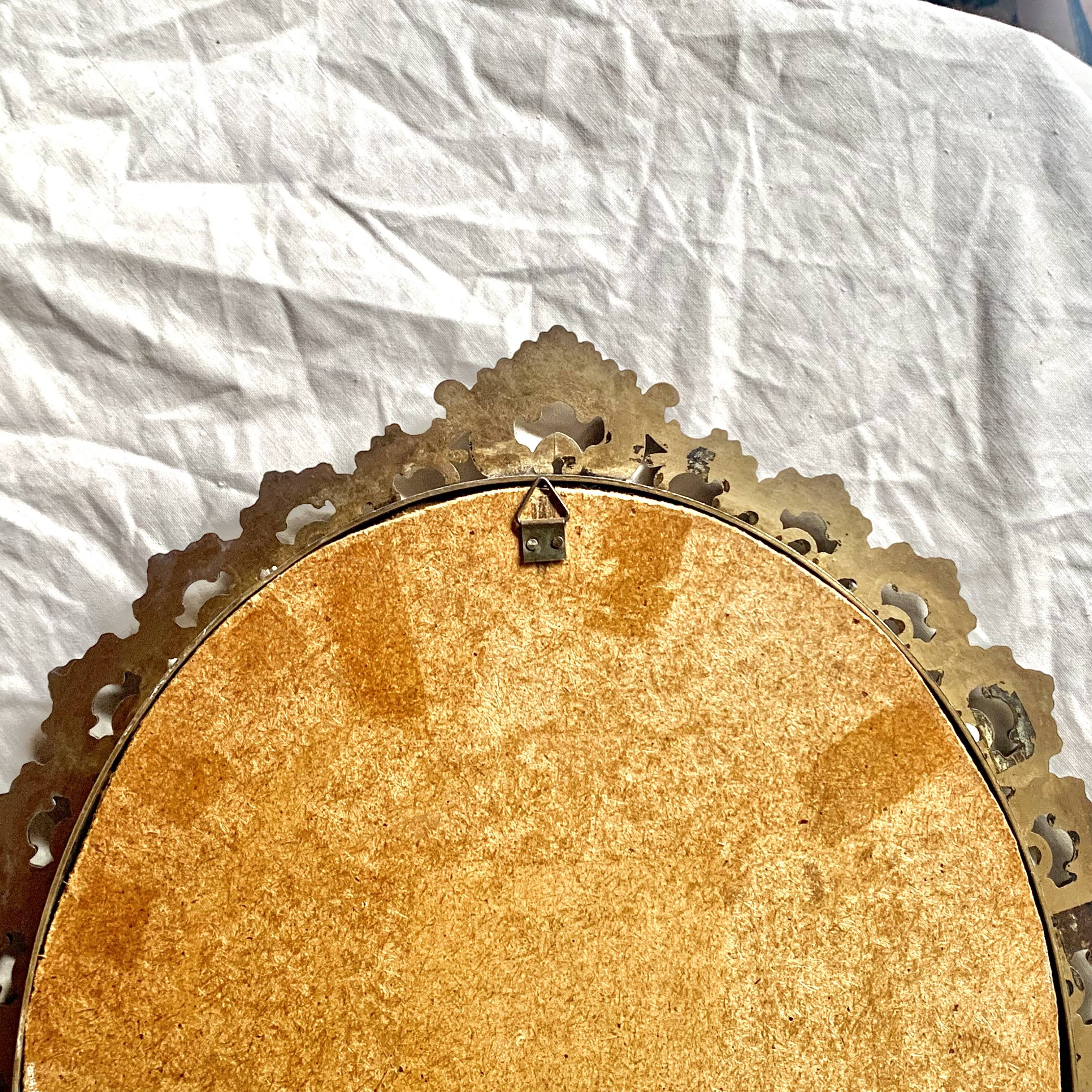 Old oval wall mirror in gilded brass