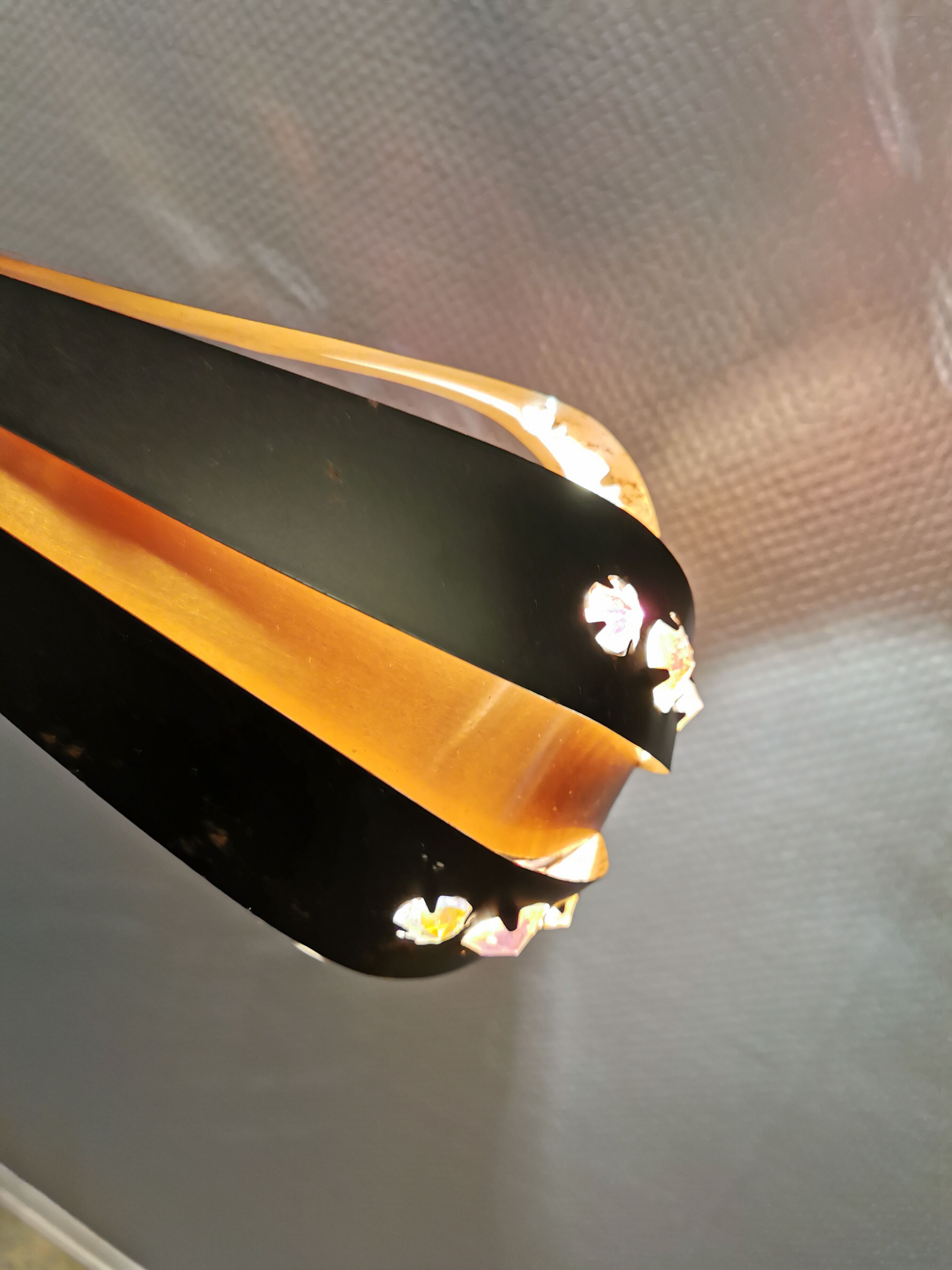 Hanging lamp in thin metal pieces, copper colored and black with prisms.