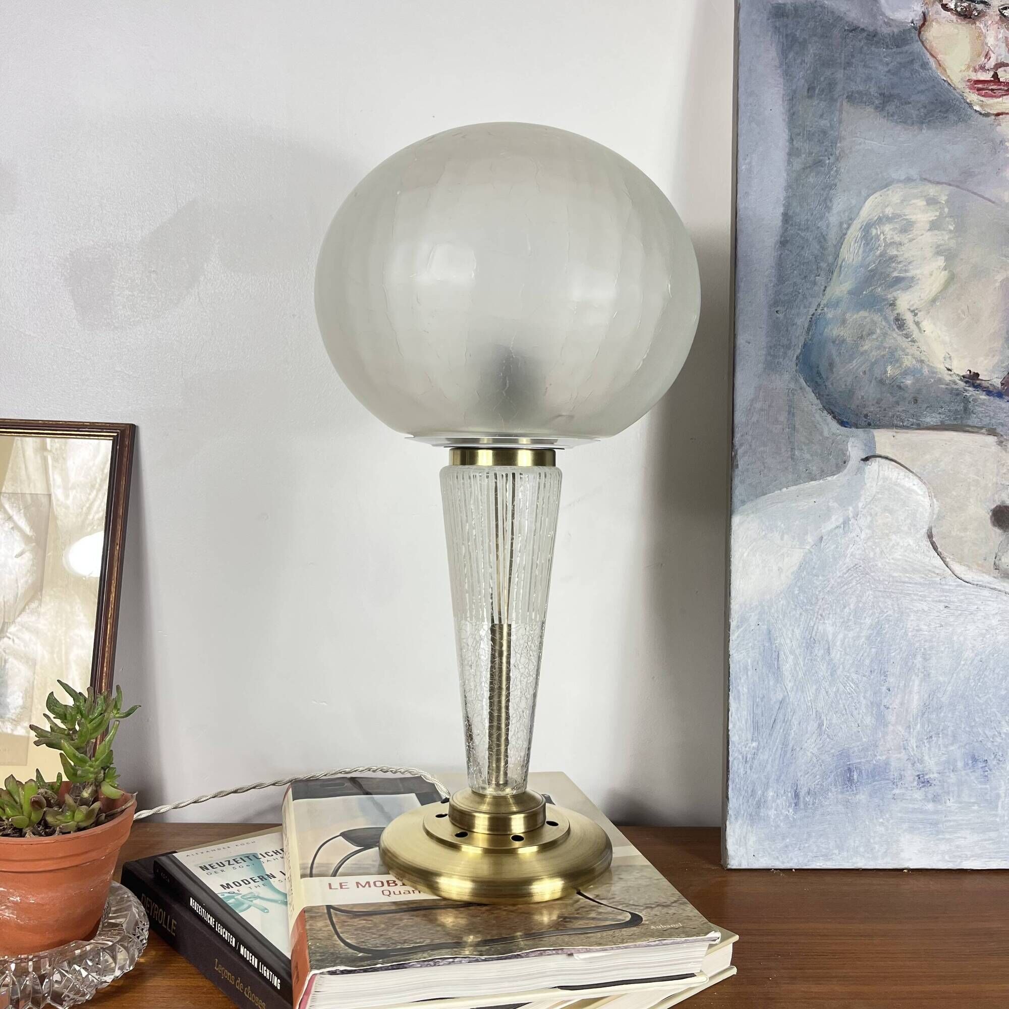 Large globe table lamp with a cracked glass base and brass stand.