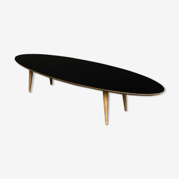 Table basse ovale avec un plateau noir et des pieds tournés en chêne