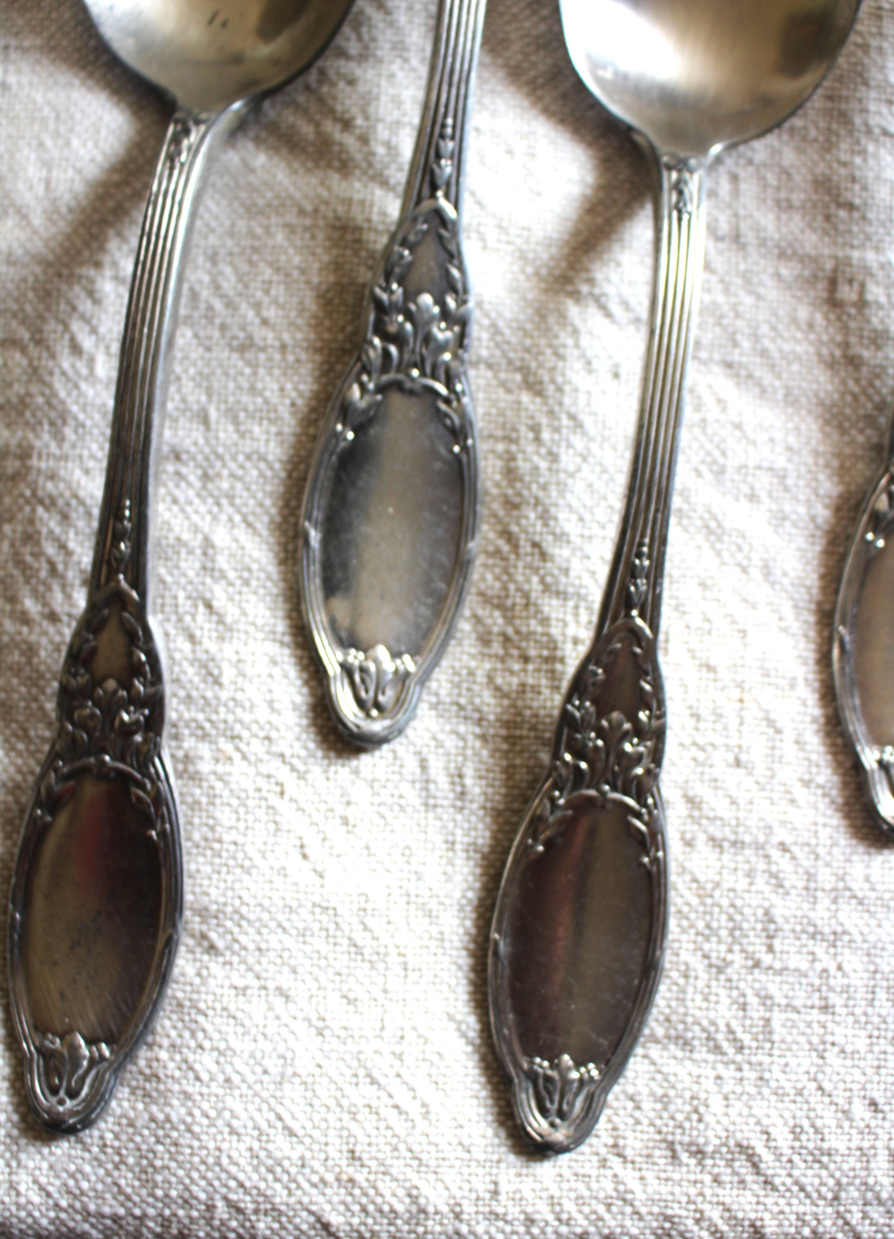 A set of 6 silver-plated metal soup spoons with foliage design.