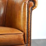 Neat and subtle sheepskin club chair, finished with decorative studs and a fixed seat cushion