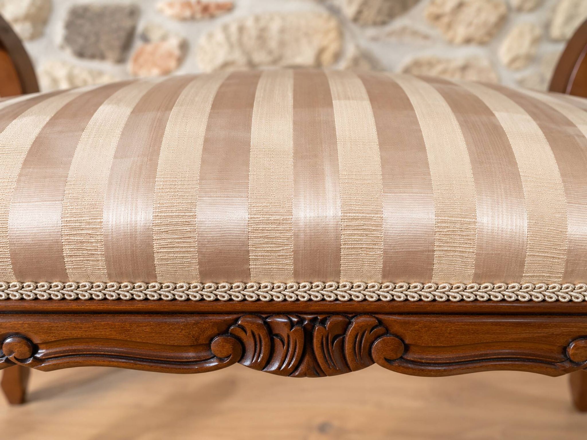Two-seater bench in carved wood, with curved armrests.