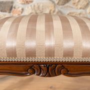 Two-seater bench in carved wood, with curved armrests.