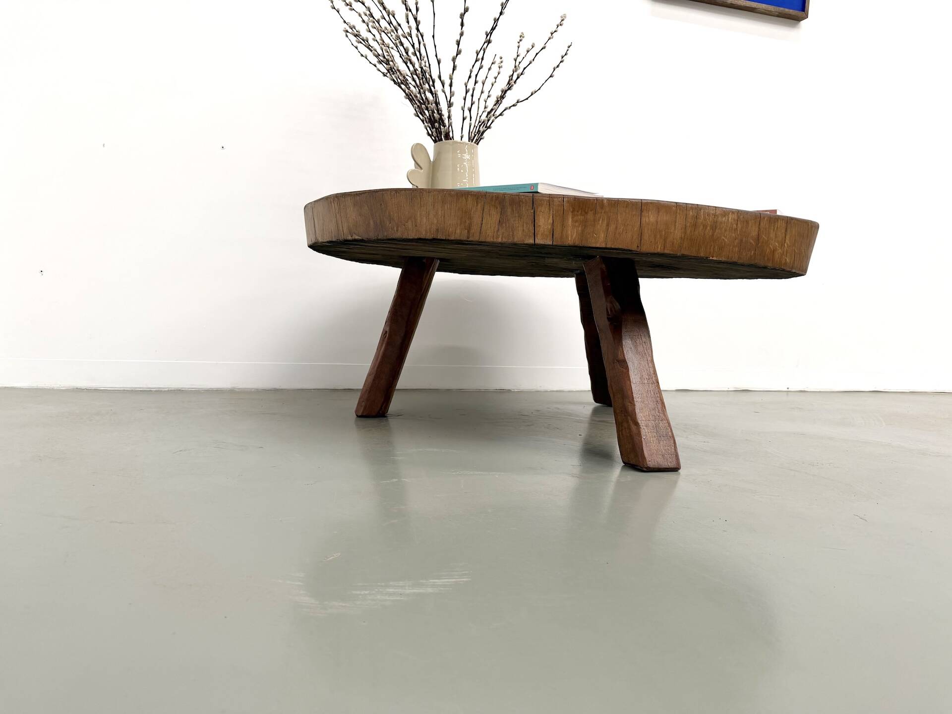 Brutalist coffee table in solid teak, monolithic slab, tripod base.