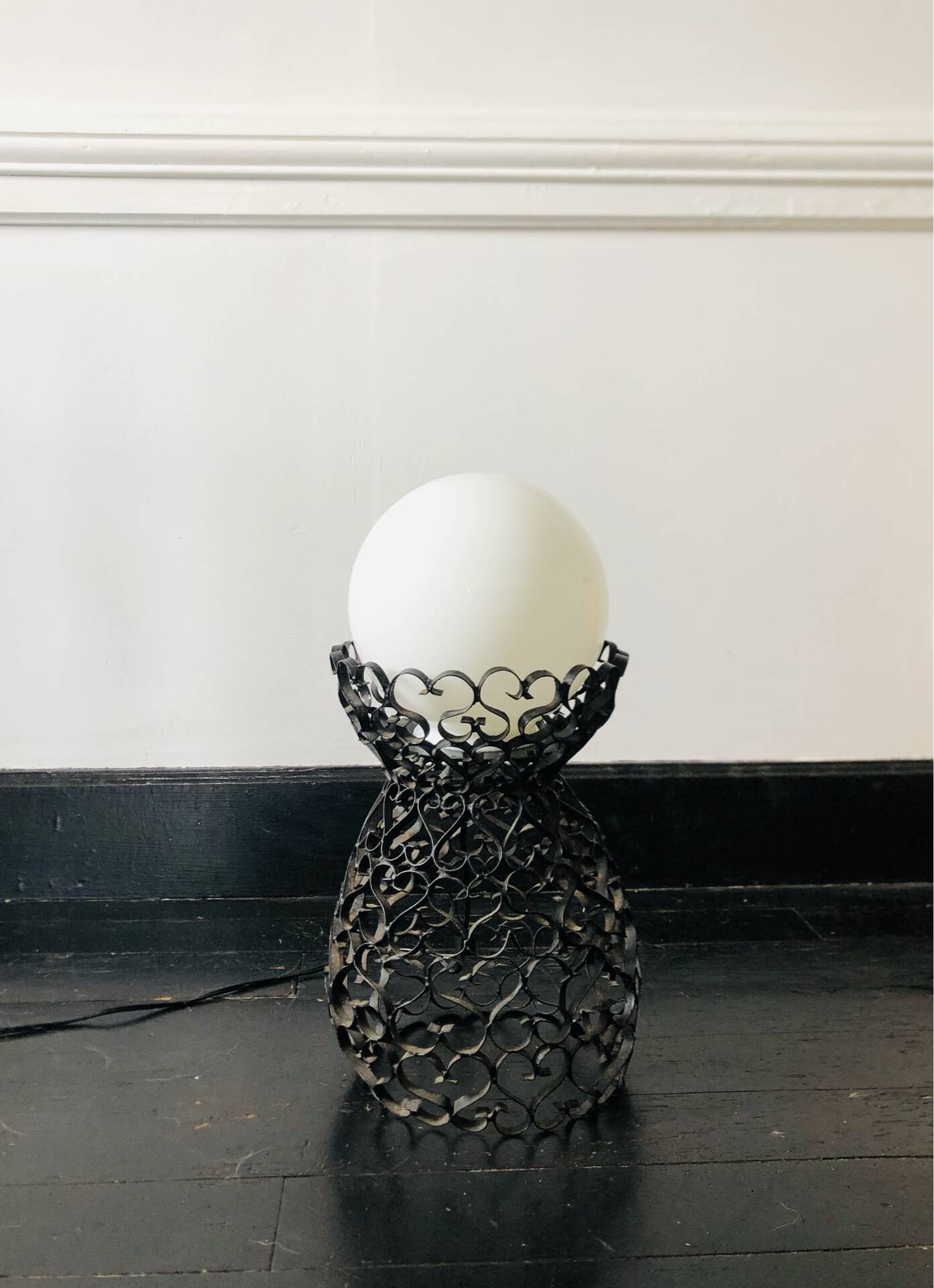 Handcrafted wrought iron lamp with a white opaline globe.