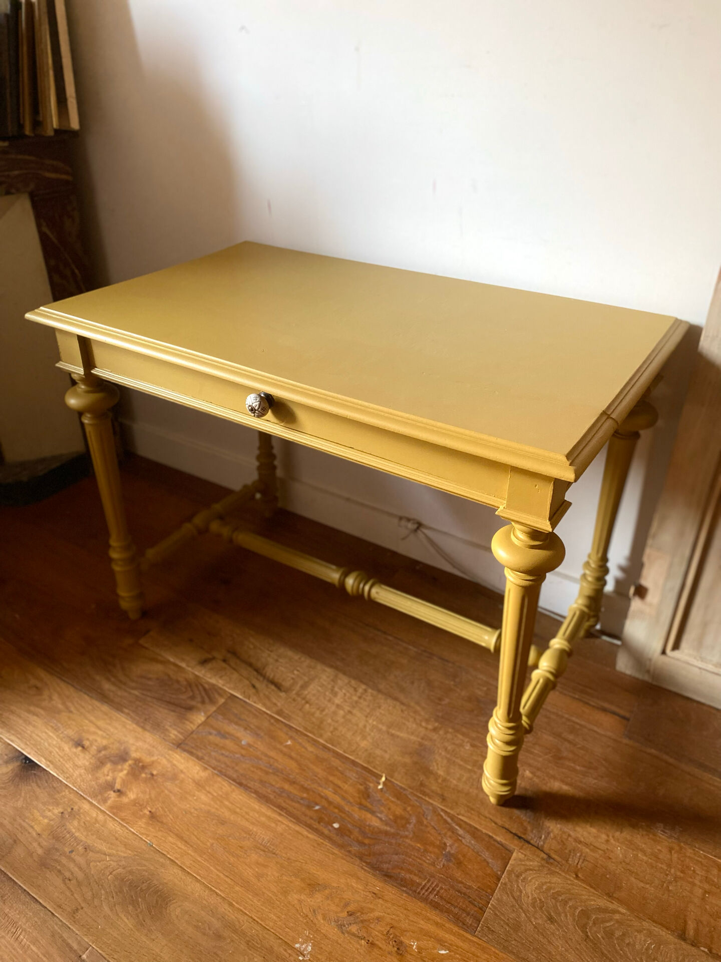Desk table from the late 19th century, painted mustard, with turned stretcher.