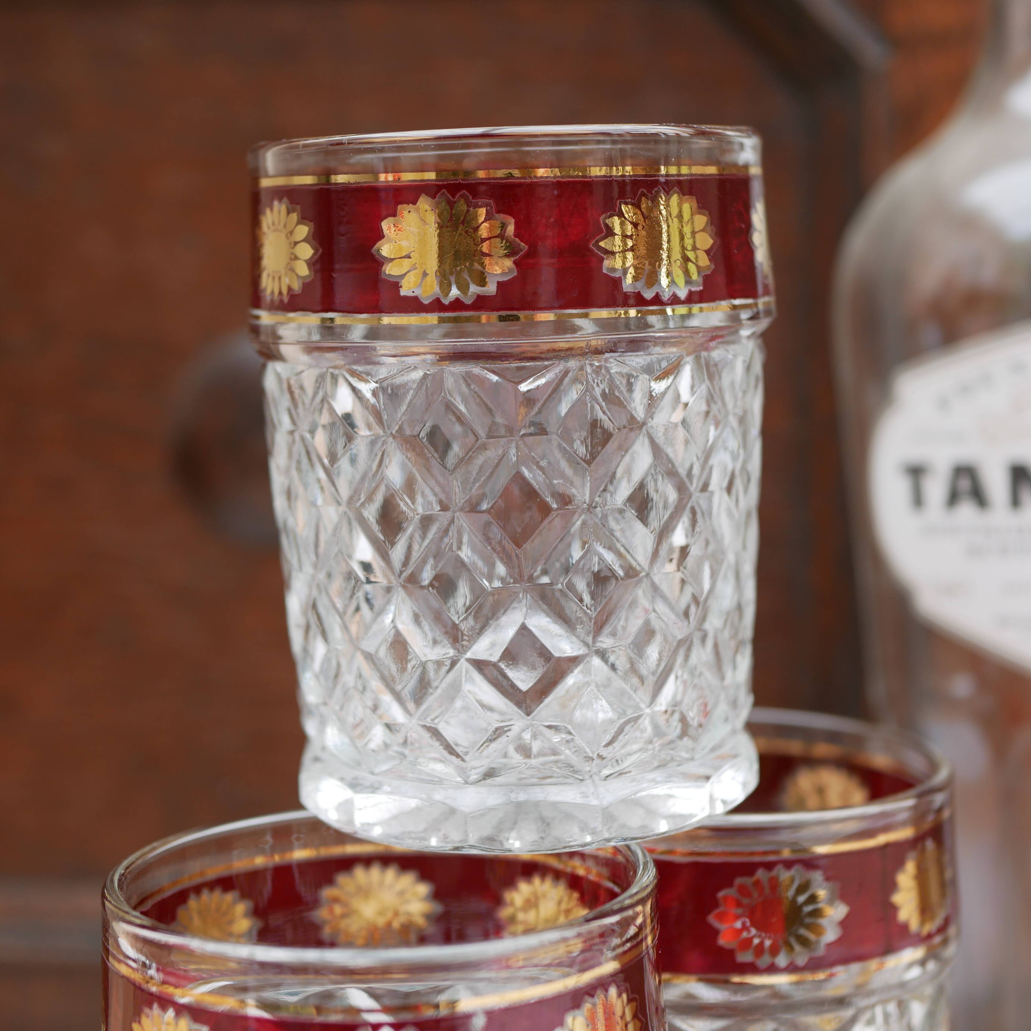 Six pressed glass whisky glasses with red and gold rims