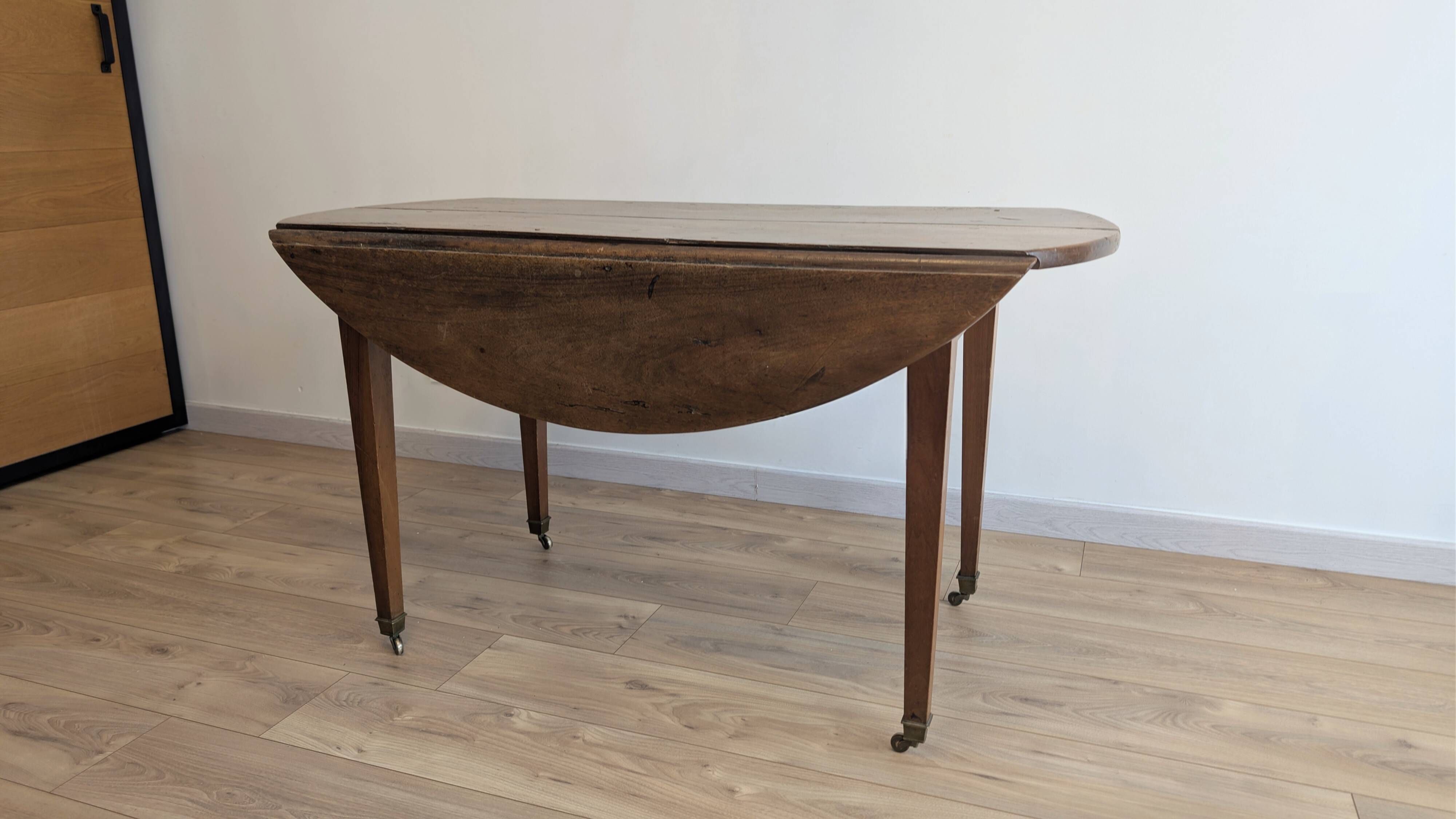 Antique wooden folding table with a patina and brass wheels.
