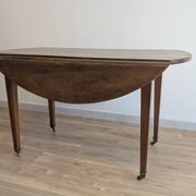 Antique wooden folding table with a patina and brass wheels.