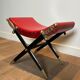 Neoclassical curule stool in red leather, decorated with crossed swords in bronze and metal covered in black leather.