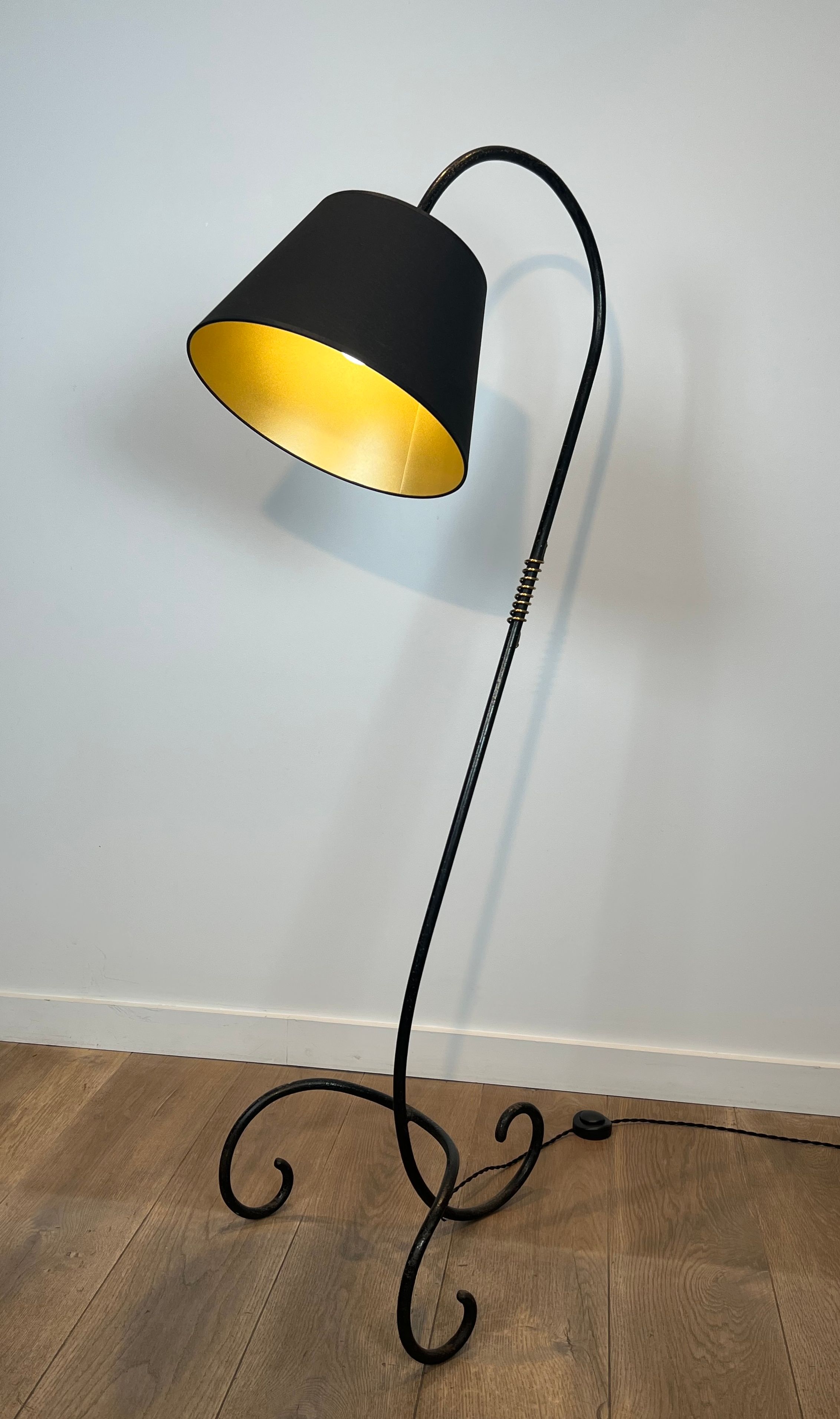 Design floor lamp in black lacquered metal and brass.