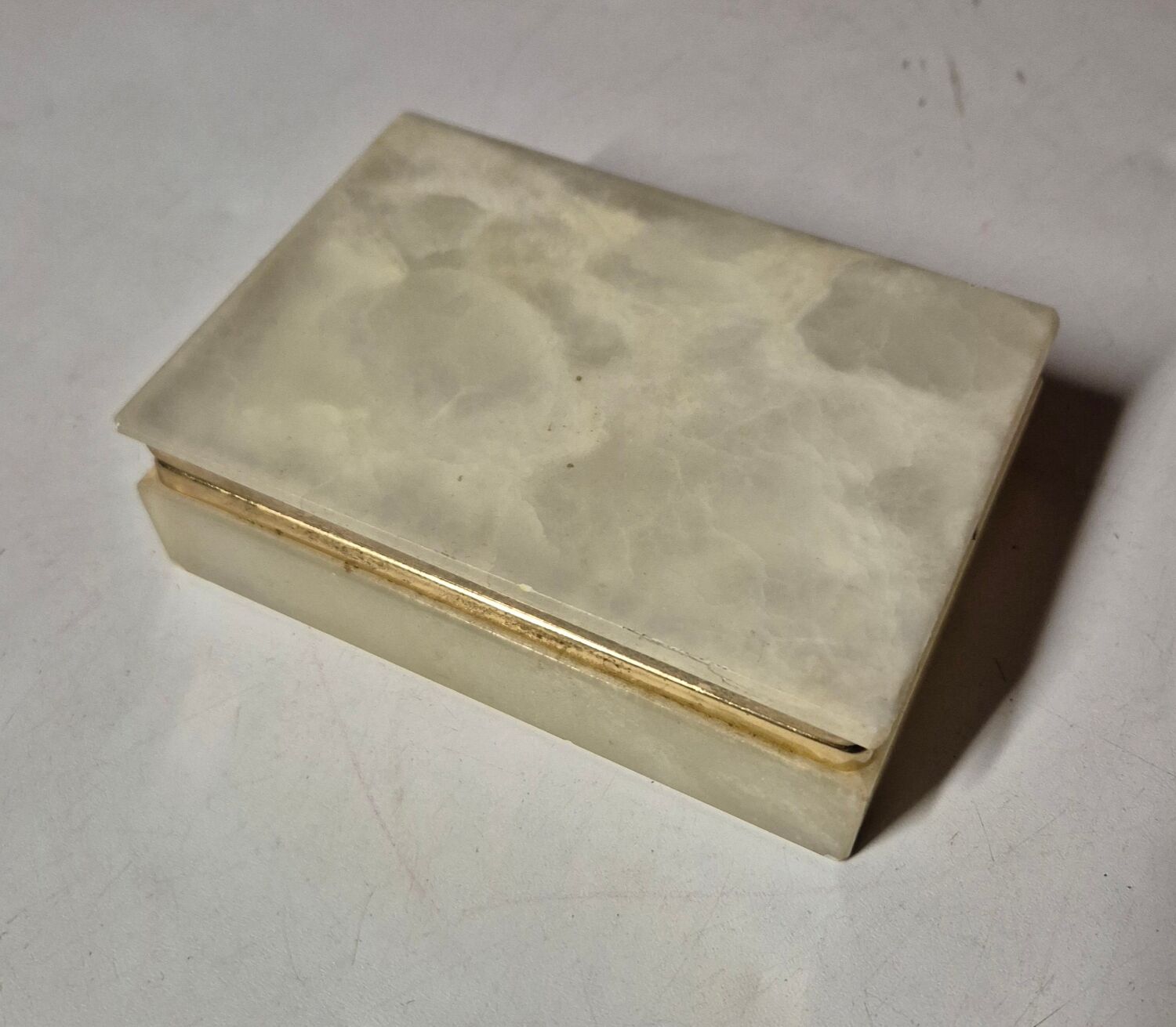 Rectangular light onyx jewellery box with brass trim, empty.