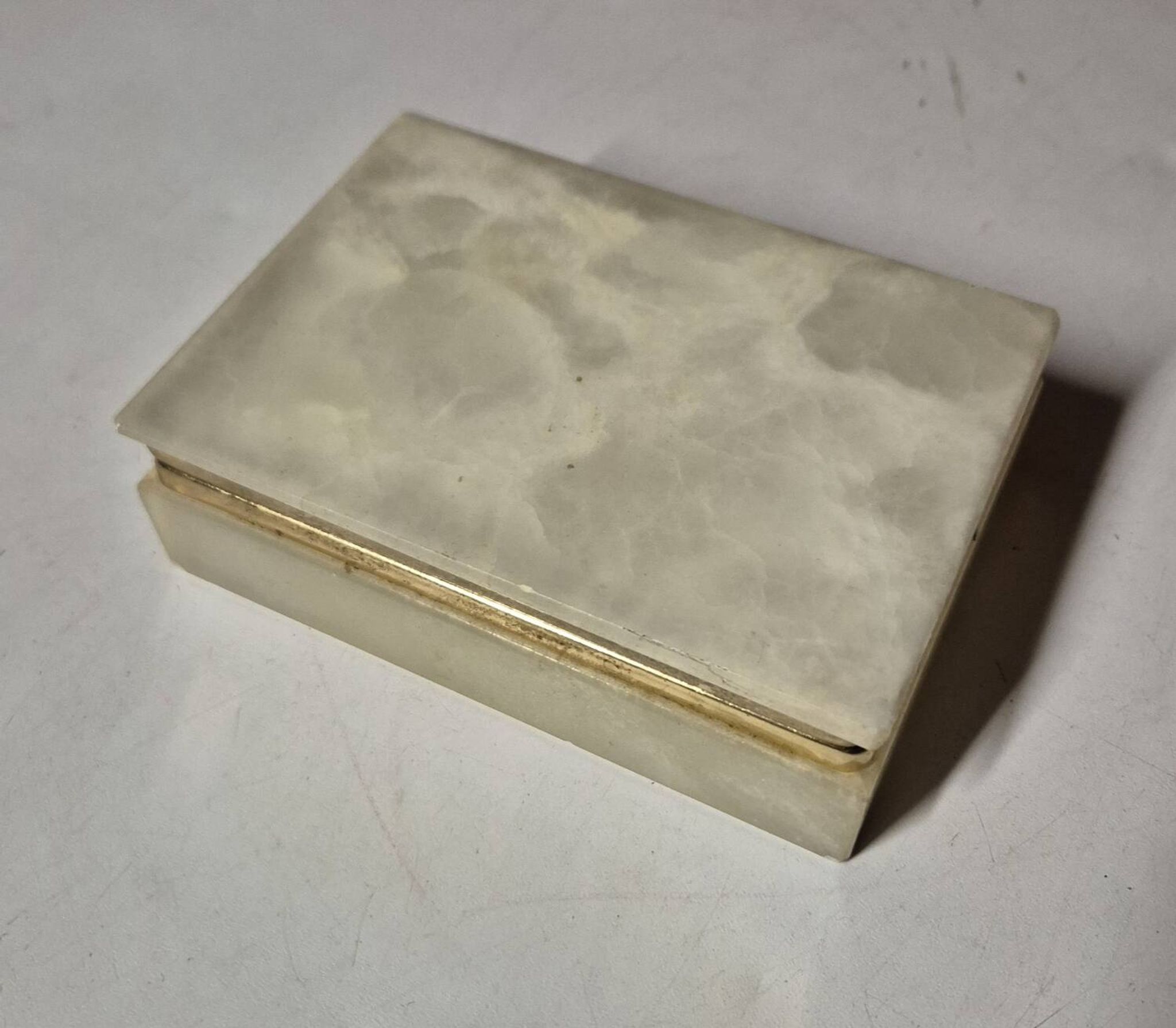Rectangular light onyx jewellery box with brass trim, empty.