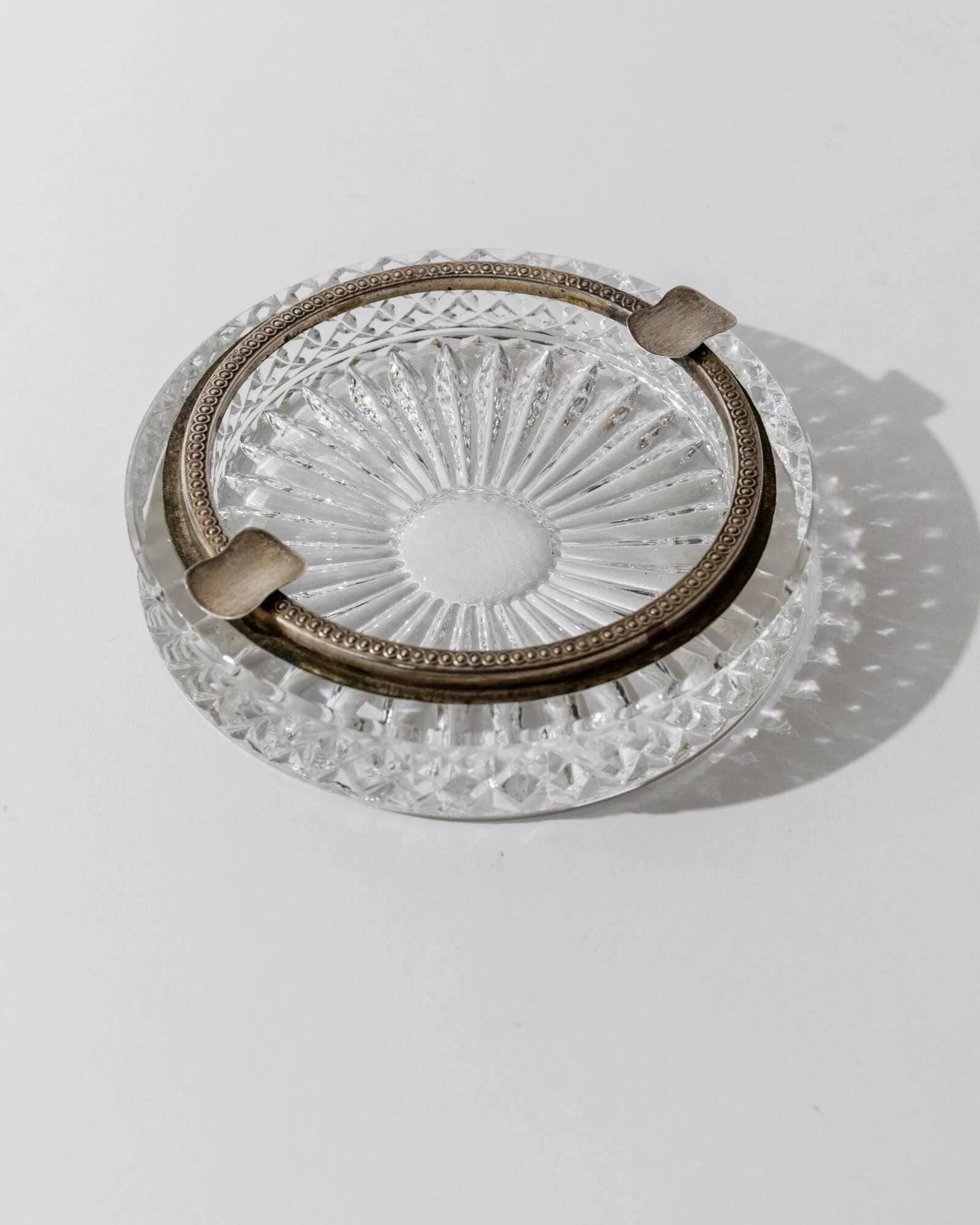 Vintage crystal glass ashtray from the 1920s, silver-edged with a textured pattern, Art Deco table decoration.
