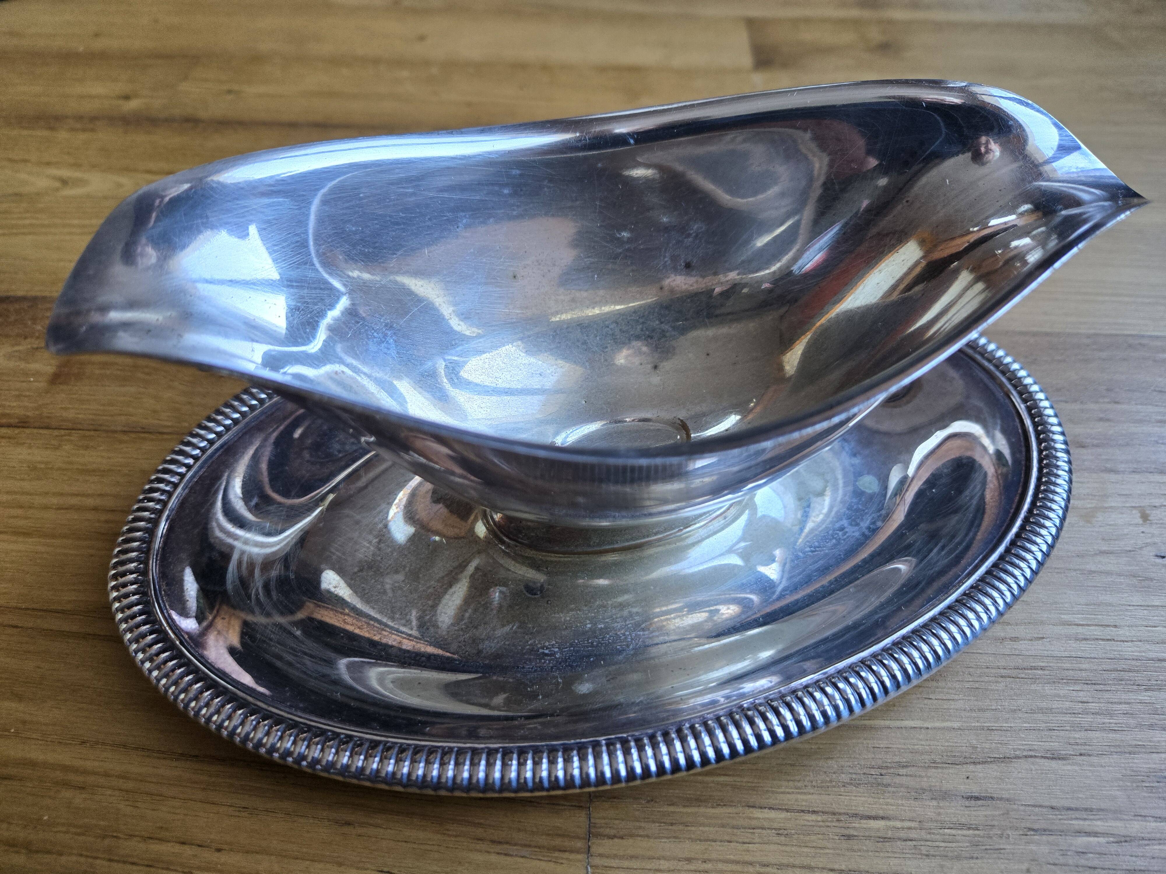 Silver-plated metal gravy boat on a stand