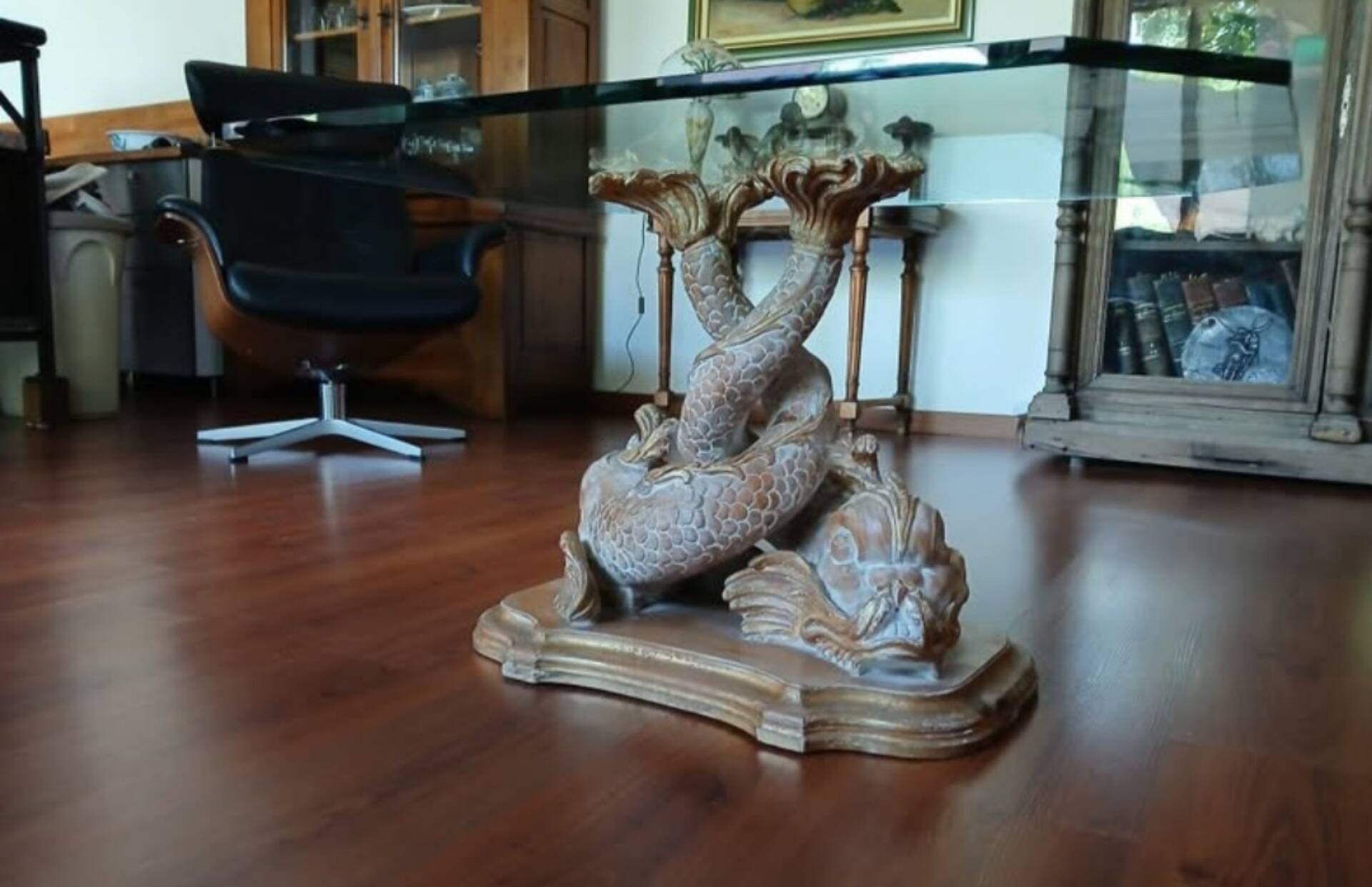 Glass table with carved wooden legs featuring intertwined fish.