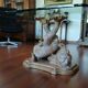 Glass table with carved wooden legs featuring intertwined fish.