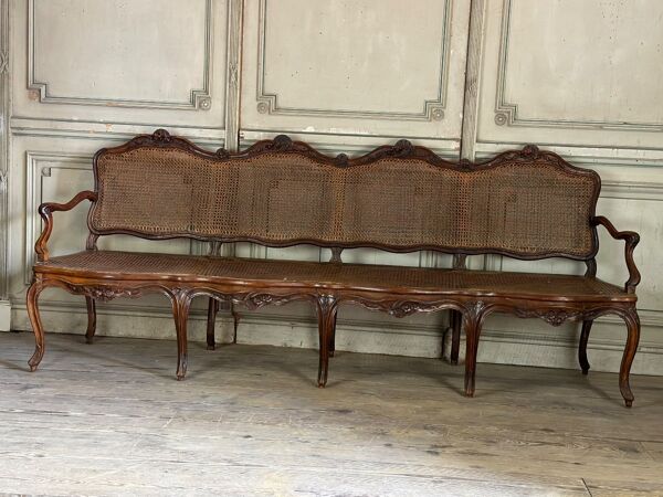 Grande banquette Louis XV en bois naturel mouluré et sculpté, France XVIIIème siècle