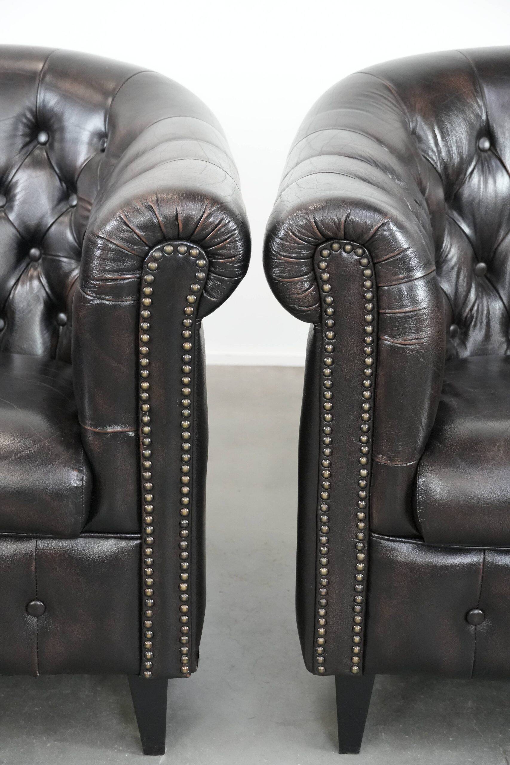 Ensemble de deux luxueux fauteuils club Chesterfield en cuir de vachette noir.