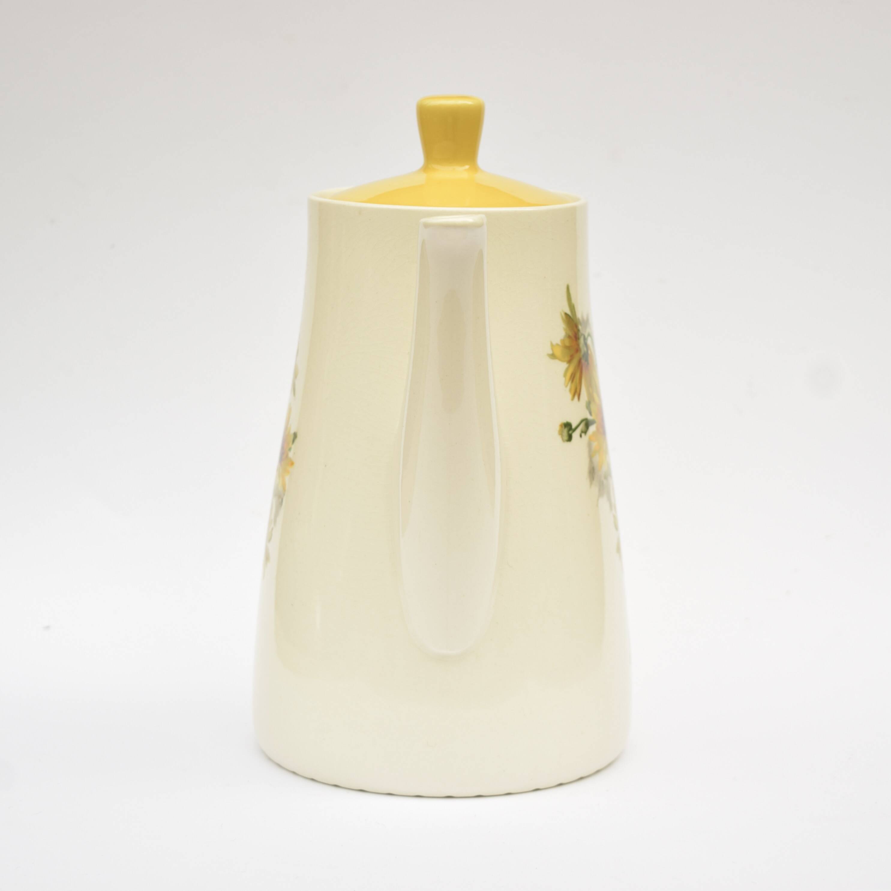 Old glazed ceramic coffee pot decorated with sunflowers