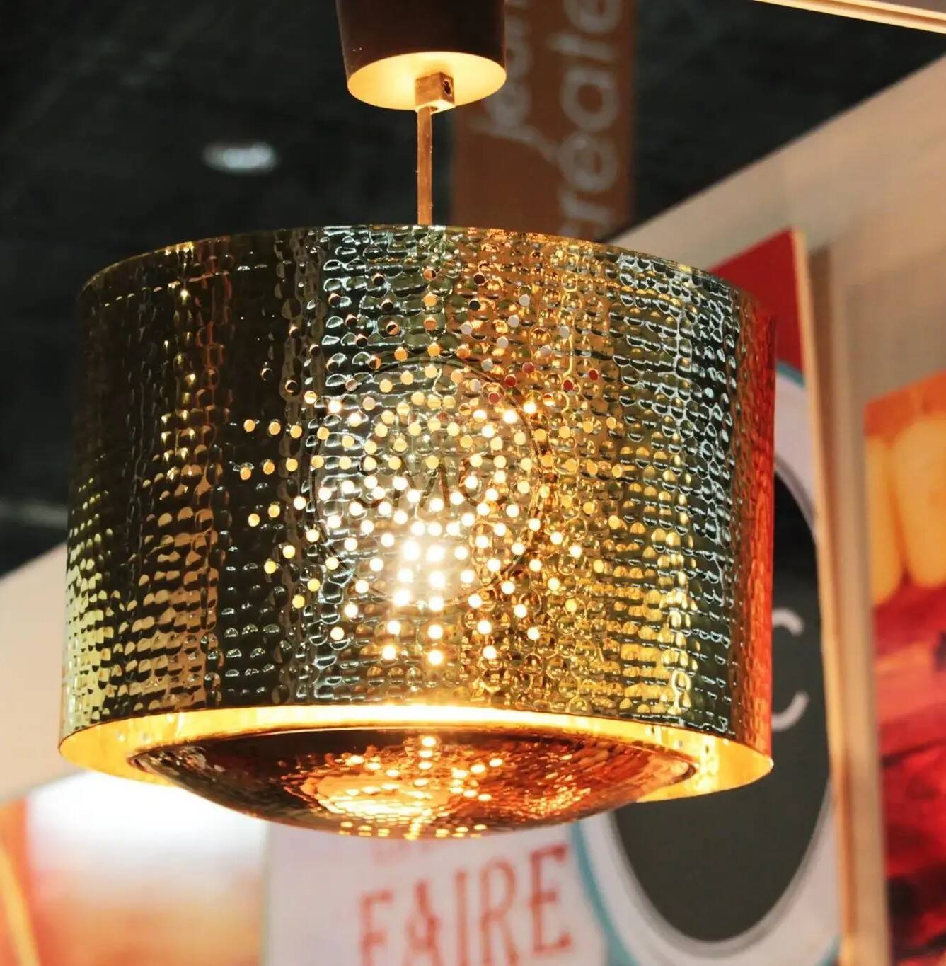 Hammered copper metal pendant light with a golden cylindrical shade.