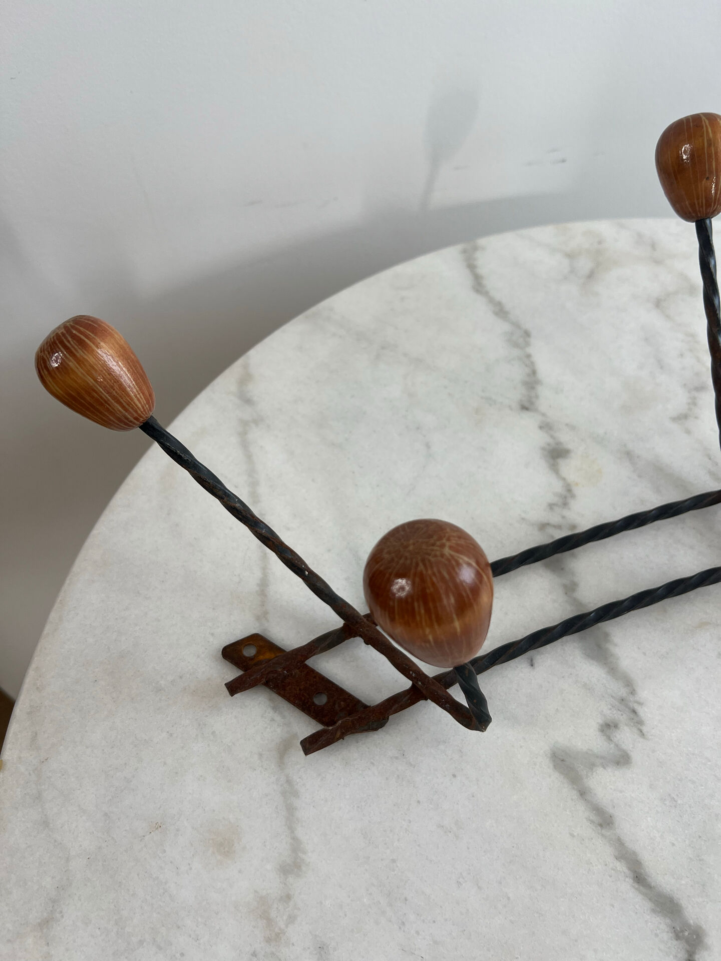 Wall-mounted coat rack in wrought iron with turned wooden knobs.