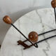 Wall-mounted coat rack in wrought iron with turned wooden knobs.