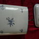 Old wall fountain in enamelled sheet metal decorated with blue flowers on a white background