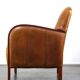Luxurious cowhide Art Deco design armchair with wooden armrests and cognac-colored leather
