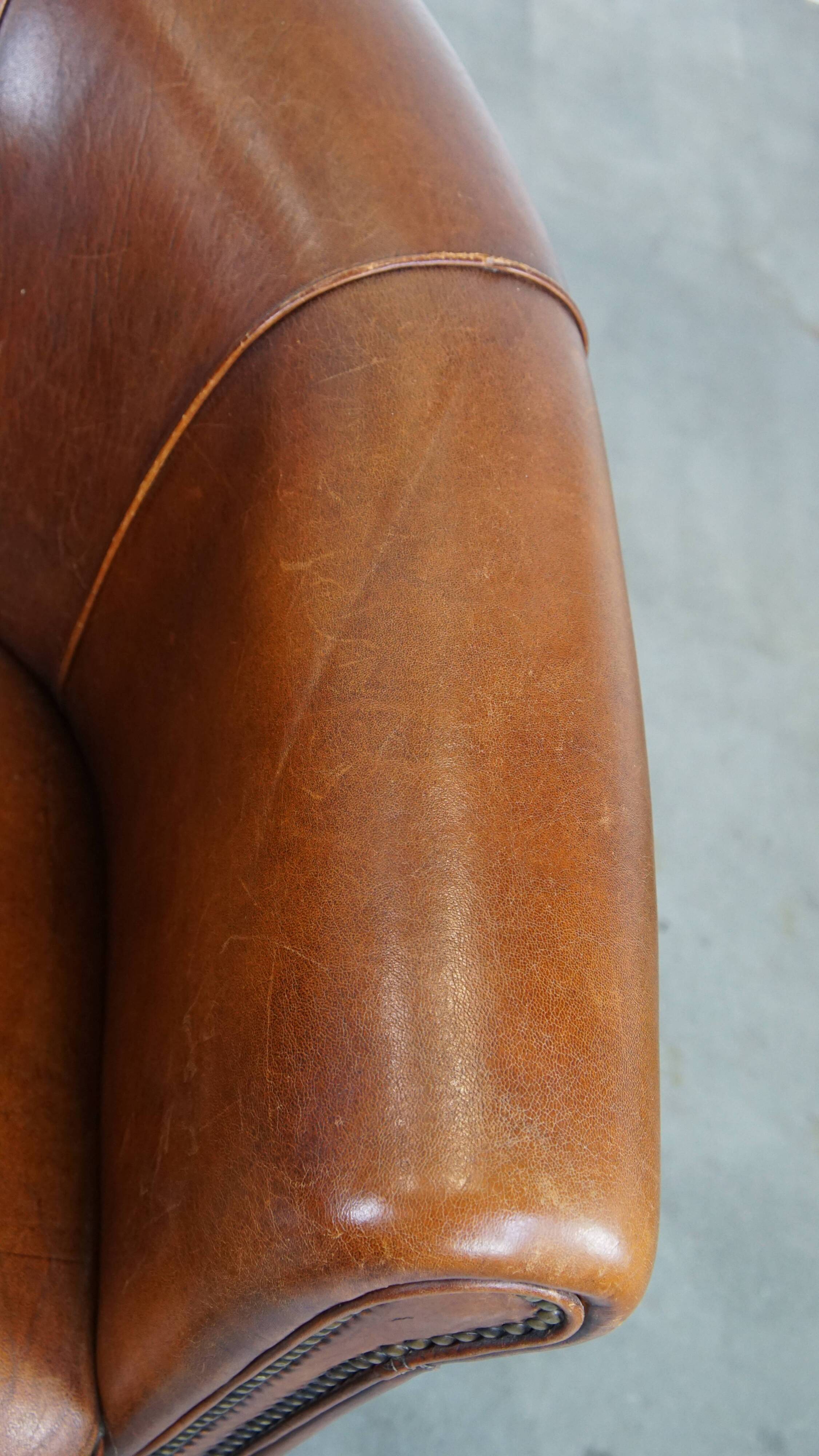 Sheep leather club chair in a cognac color and finished with piping