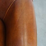 Sheep leather club chair in a cognac color and finished with piping