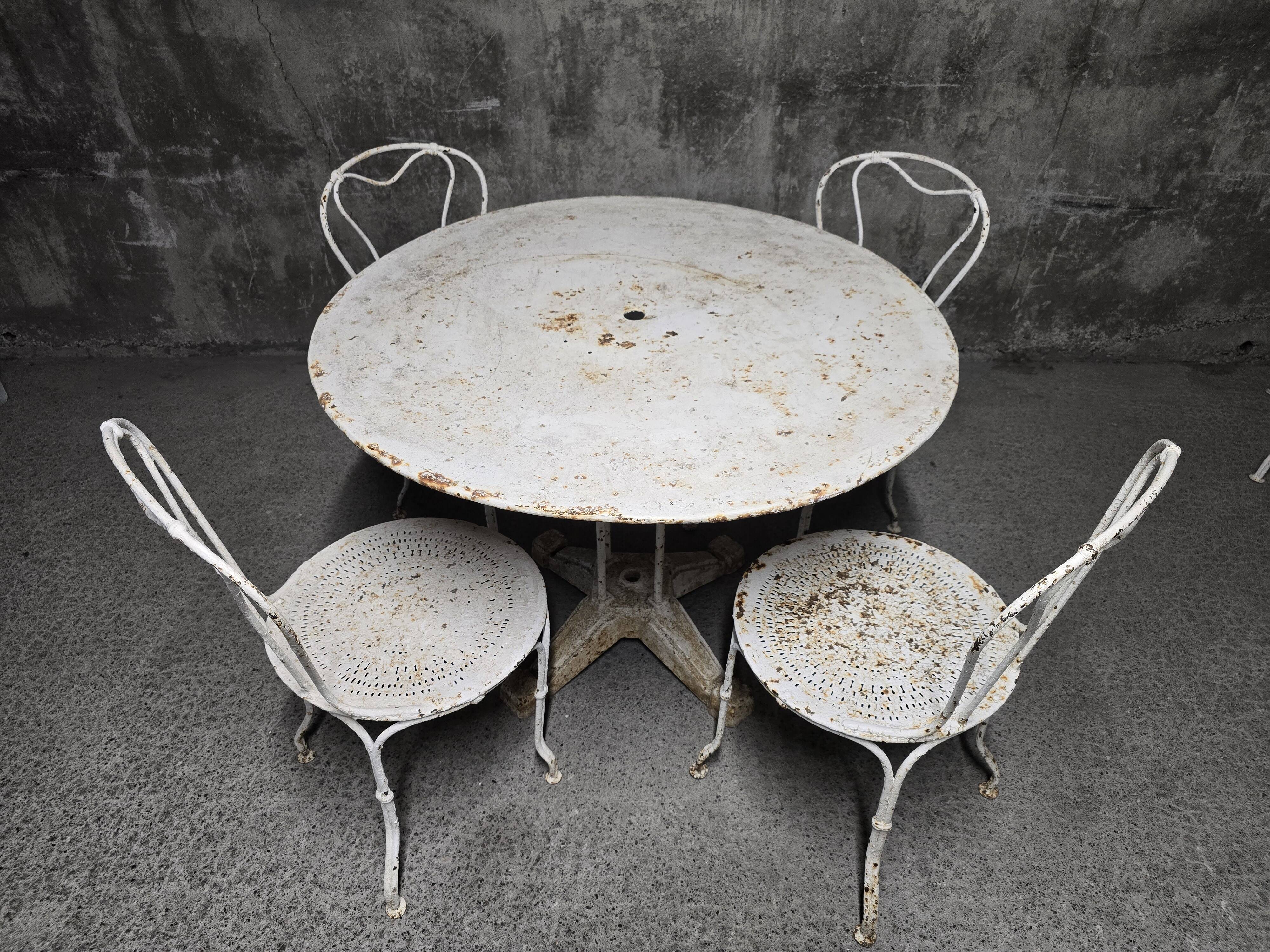 Antique painted wrought iron garden furniture, round table and four chairs.
