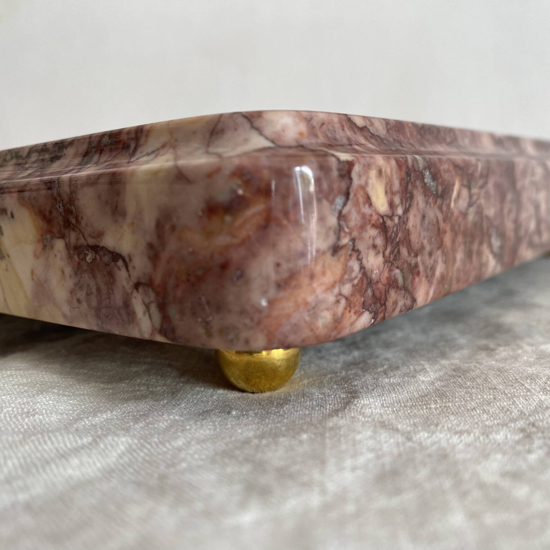Pink marble trivet with brass ball feet.