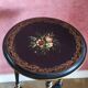 Tripod stool in blackened wood with painted floral decoration.