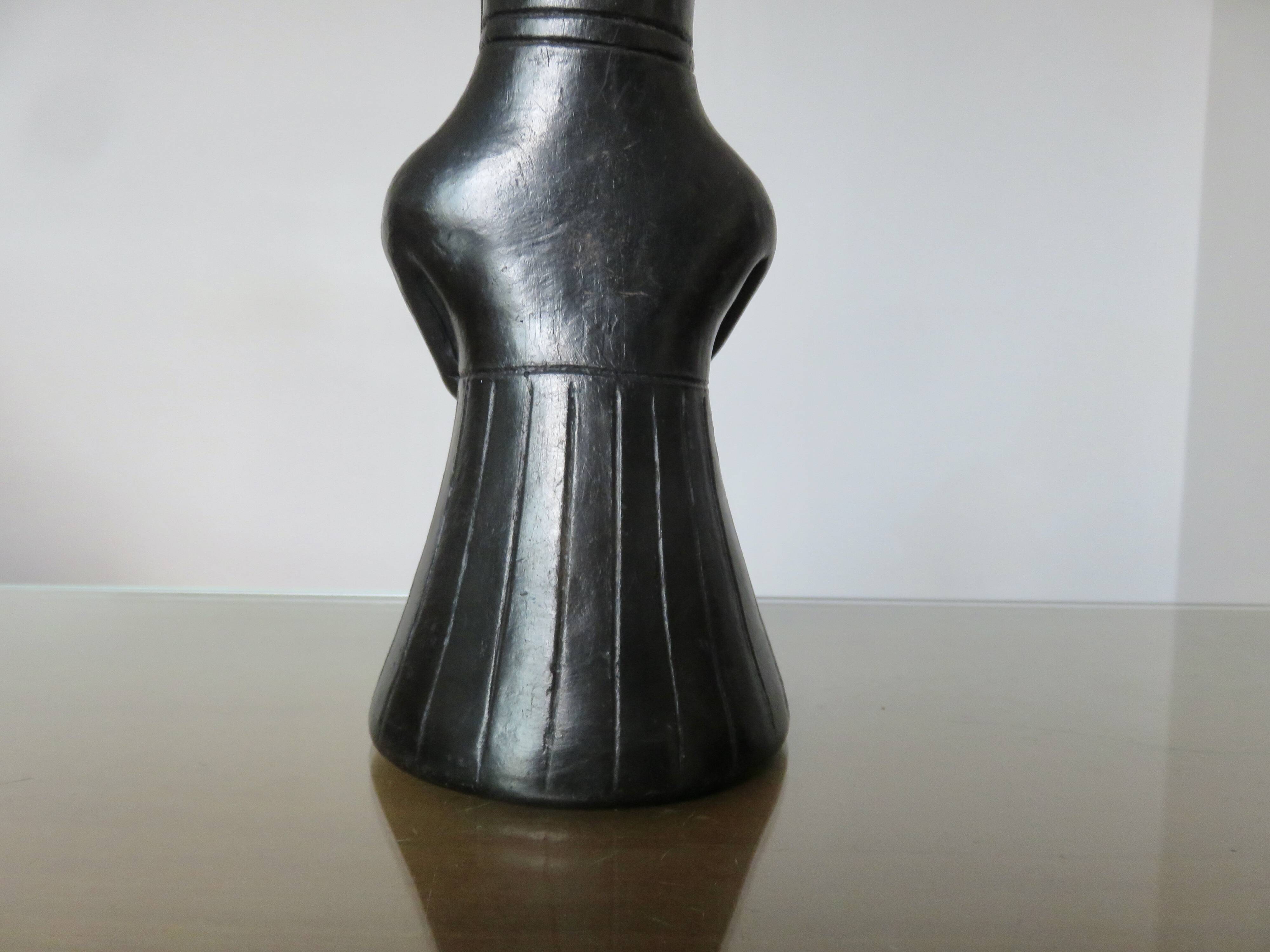 Matte black ceramic sculpture representing a female tribal figure.