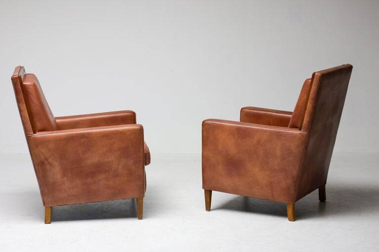 Pair of Art Deco armchairs in brown leather and teak, Netherlands, 1970s.