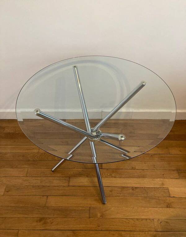 Round glass dining table with a chrome central base.