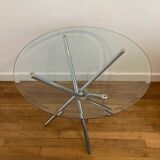 Round glass dining table with a chrome central base.